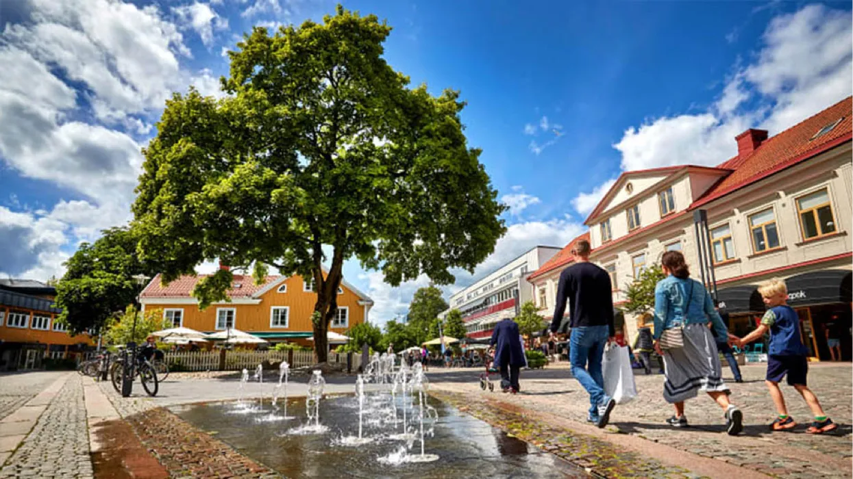 Torget i Växjö City med fontän, träd och människor i rörelse